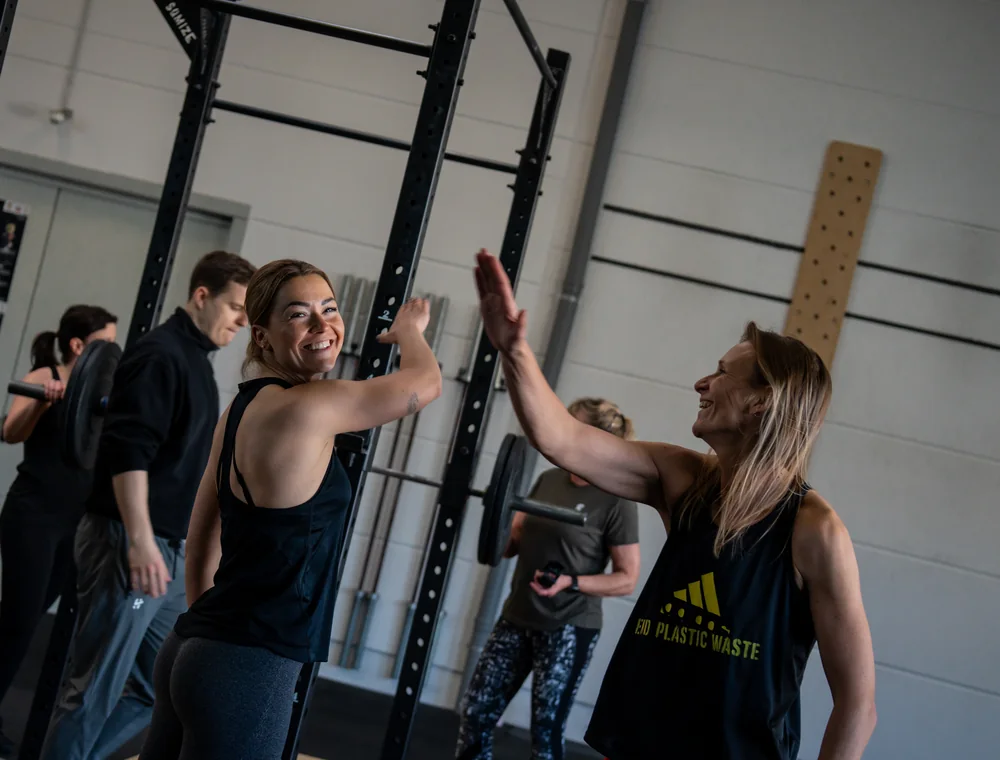 Buddy WOD bei Kings Avenue CrossFit Zwei Athletinnen klatschen sich nach dem gemeinsamen Training lachend ab