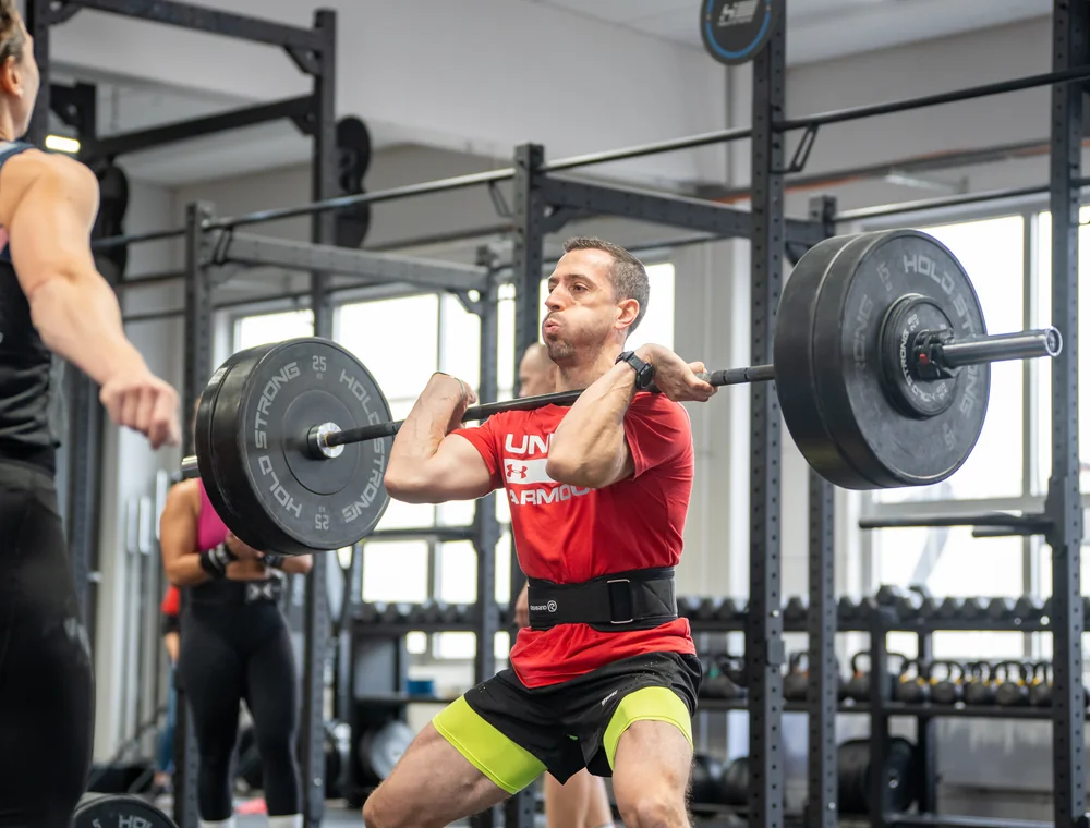 Weightlifting bei Kings Avenue CrossFit Athlet hält eine Langhantel auf Schulterhöhe beim Gewichtheben